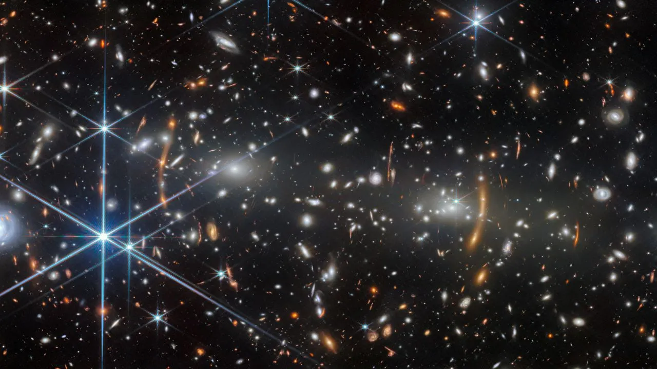 JWST turns Einstein lensing into orange arcs, revealing galaxies under 1 billion years old