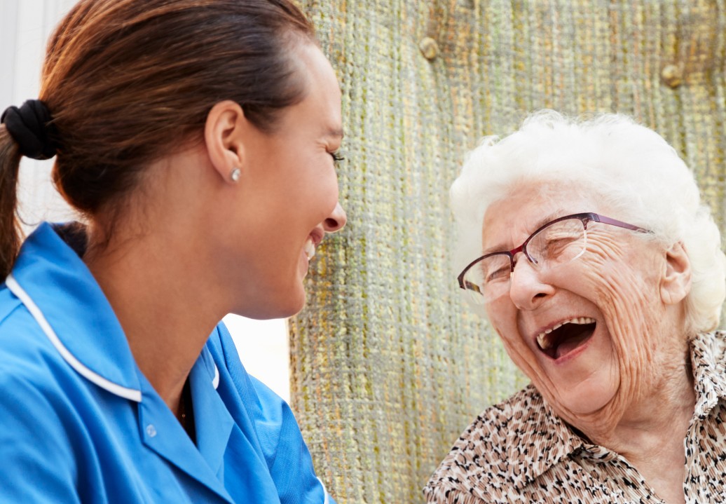 Assisted Living caregiver with senior living woman laughing about the conversation.