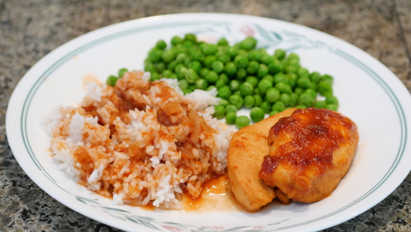 Cooked chicken and rice covered with chicken hurry sauce and peas on a plate.