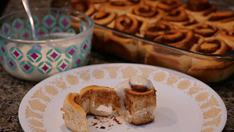 A picture of a cinnamon bun with the pan and icing.