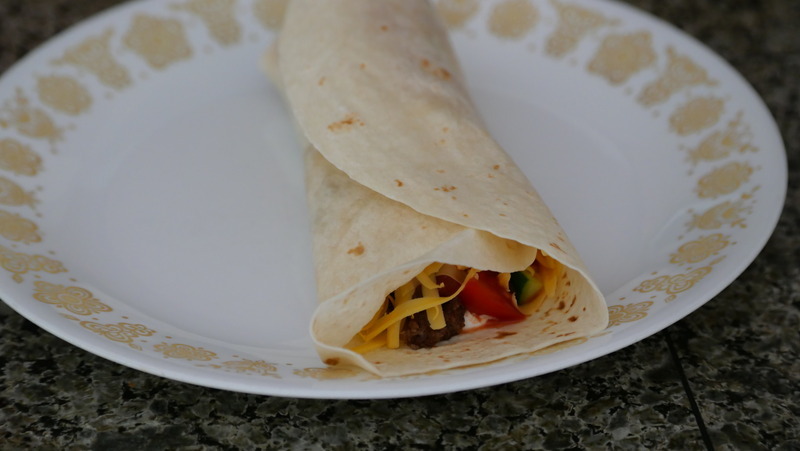 A picutre of a soft shelled taco unrolled on a plate.