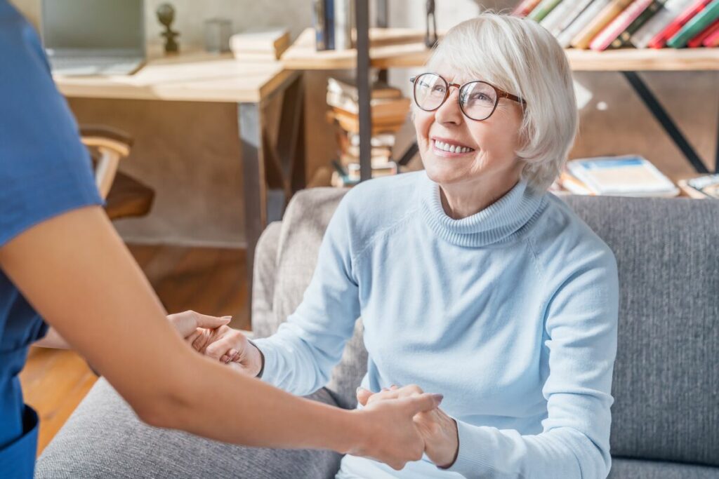 nurse helping senior woman off the couch