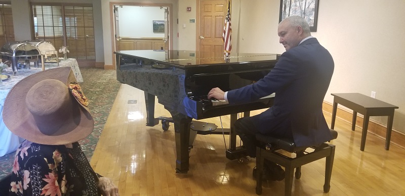 Man playing piano for Mother's Day tea event