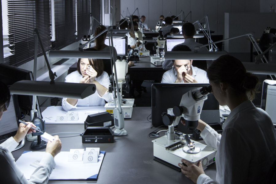 team inspecting gems with loupes and microscopes