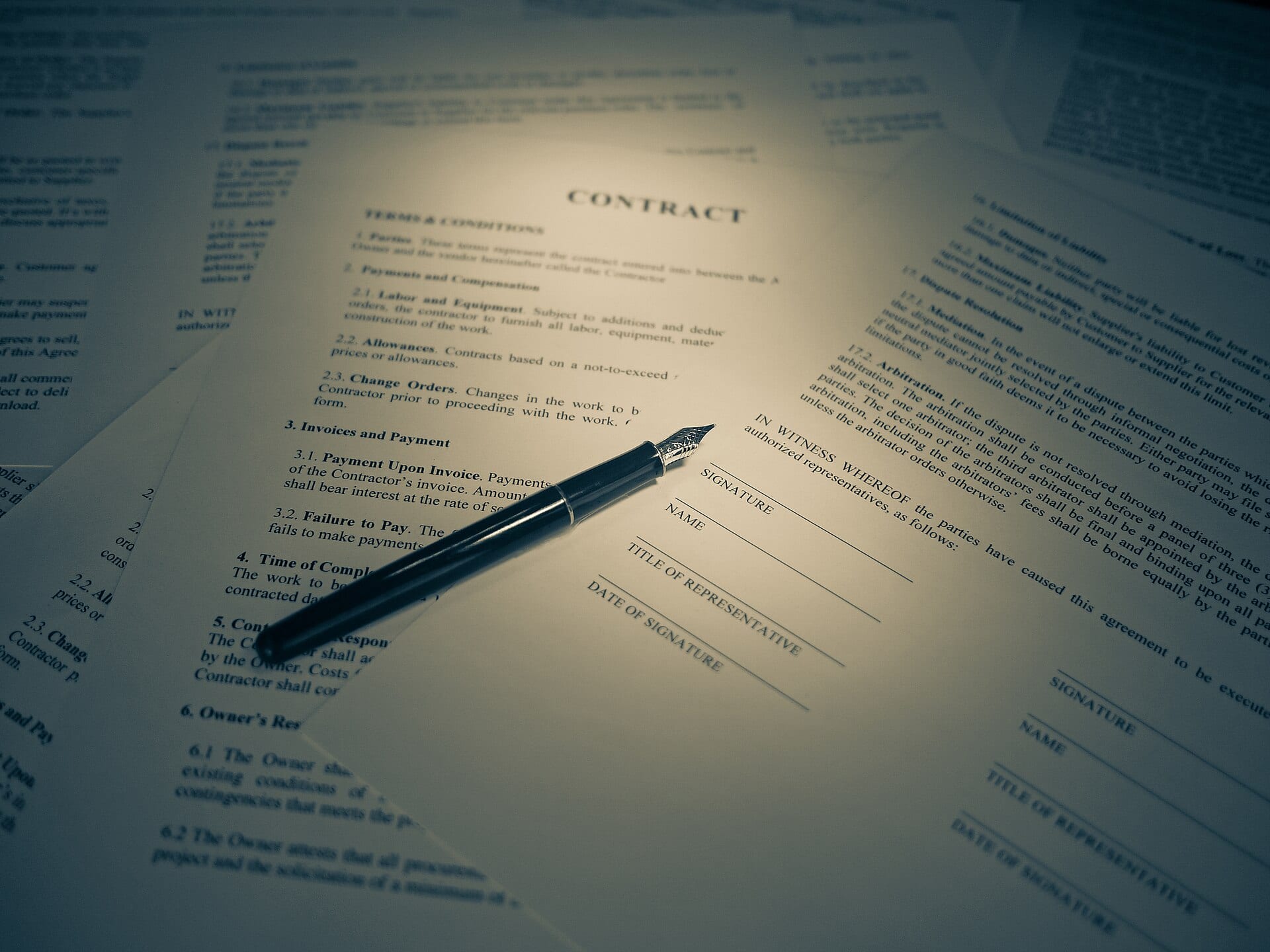 A pen resting on contract terms and a signature block
