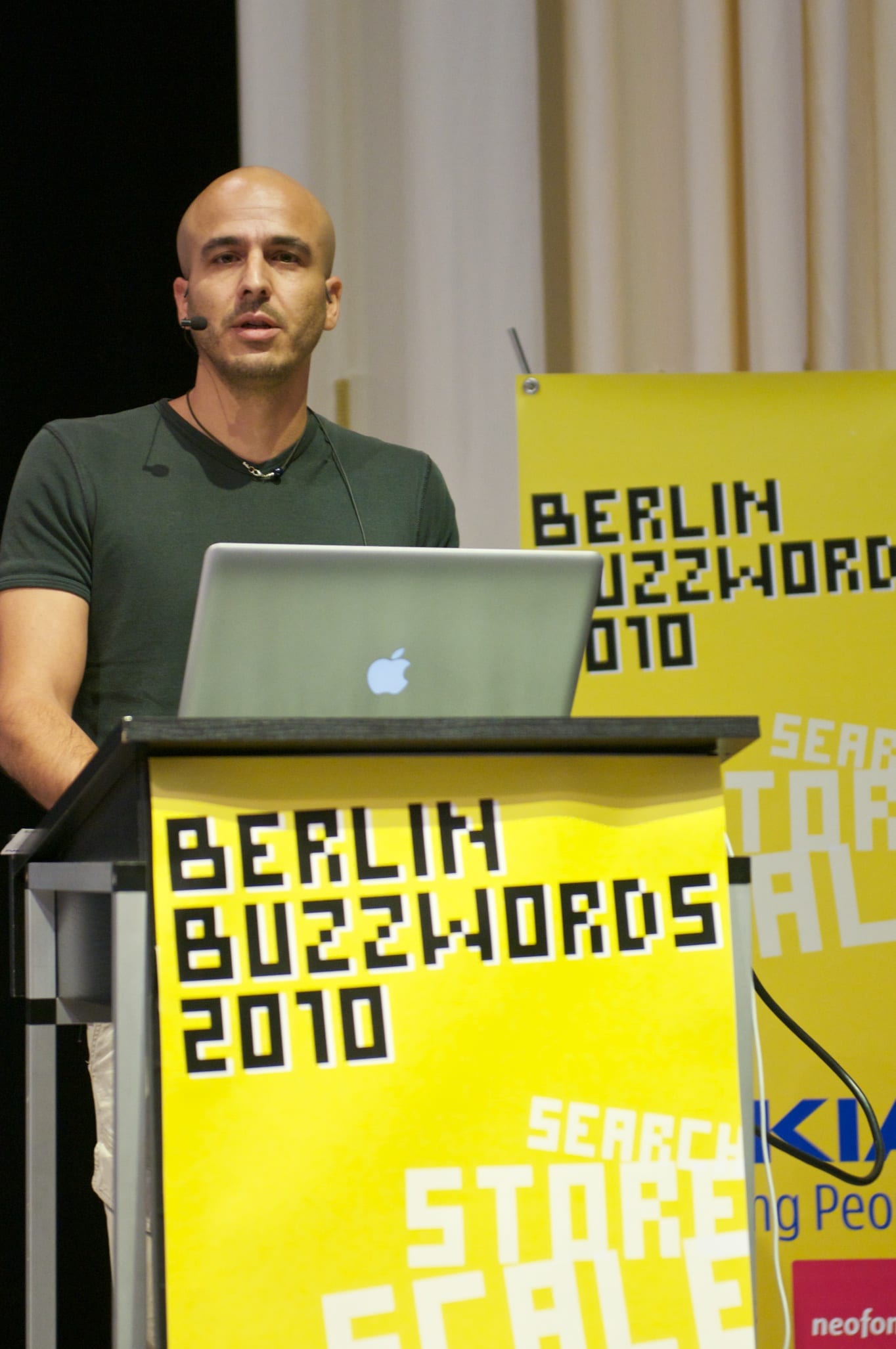 Shay Banon, founder of Elastic, speaking at a podium at Berlin Buzzwords 2010 with a laptop in front of him.