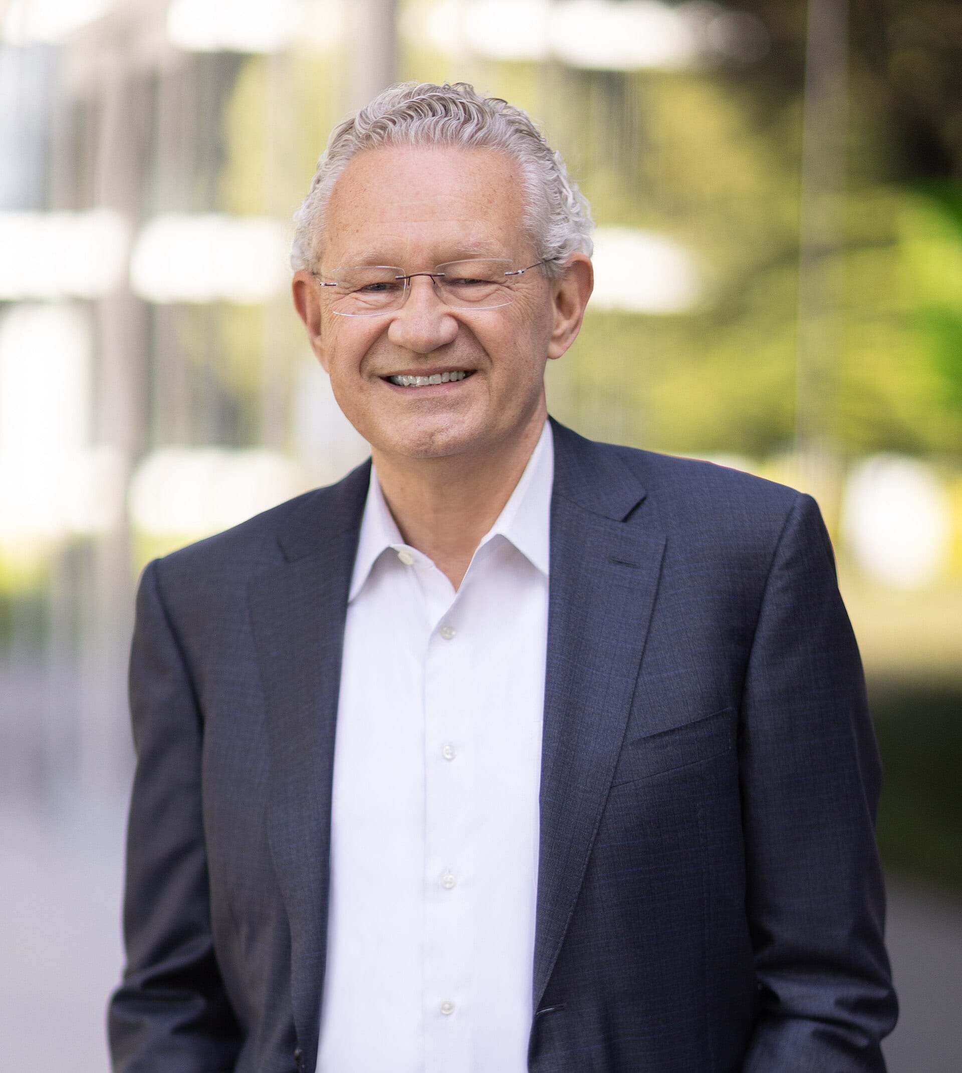 Aart de Geus, founder and executive chairman of Synopsys, smiling in a dark suit and open-collar shirt