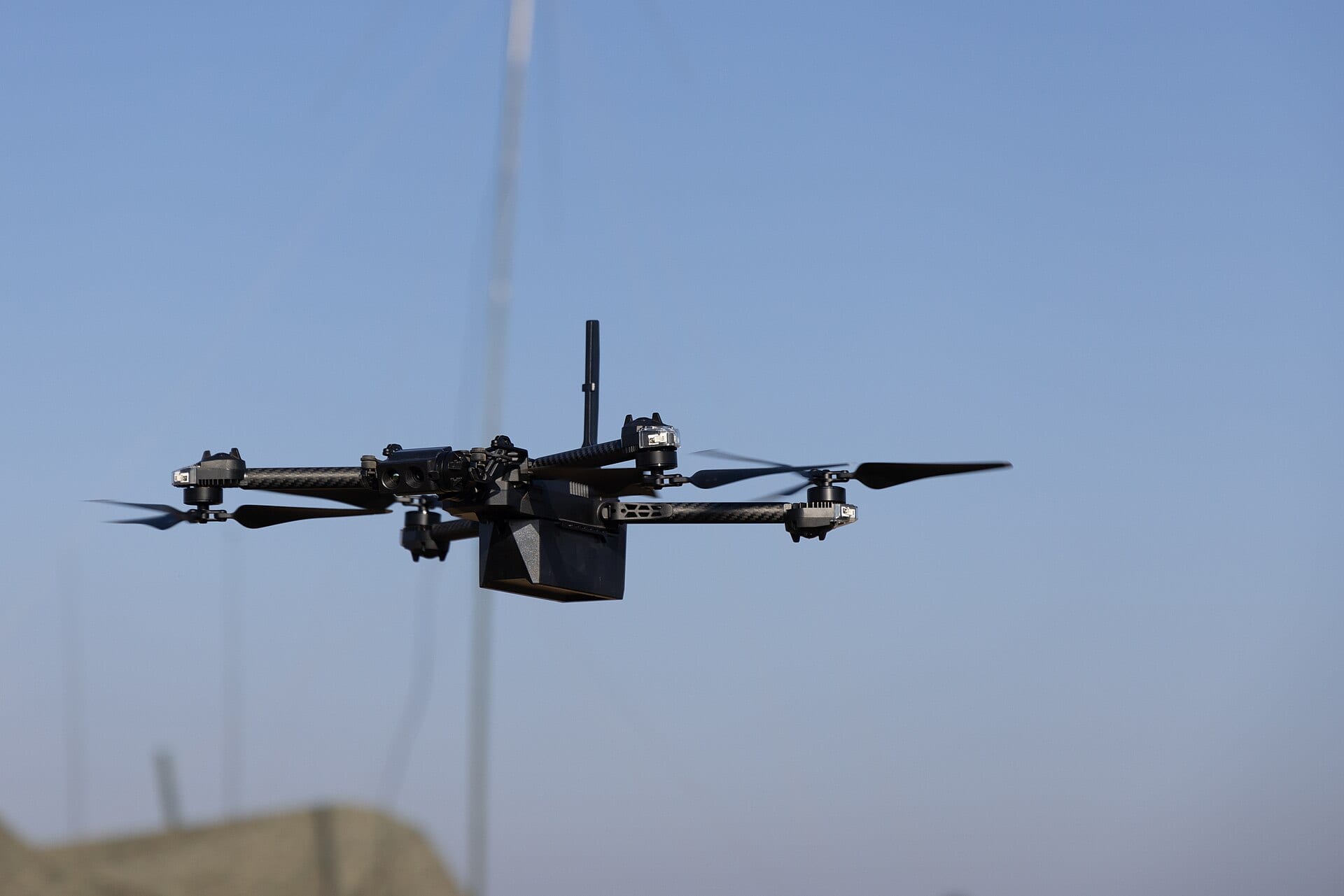 A Skydio quadcopter drone in flight against a clear blue sky