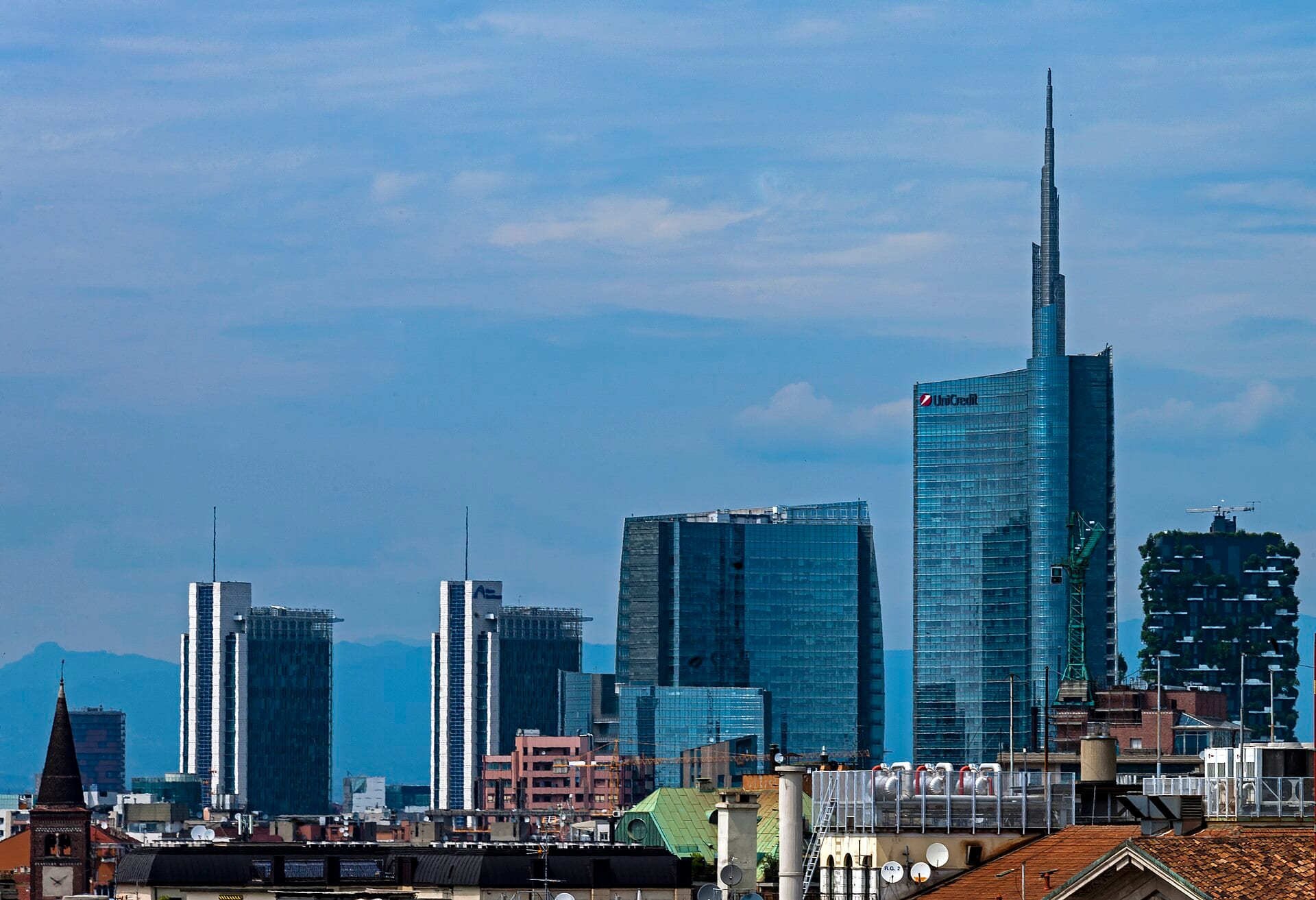 Milan's Porta Nuova business district skyline, with the UniCredit Tower and Bosco Verticale rising above the city rooftops.