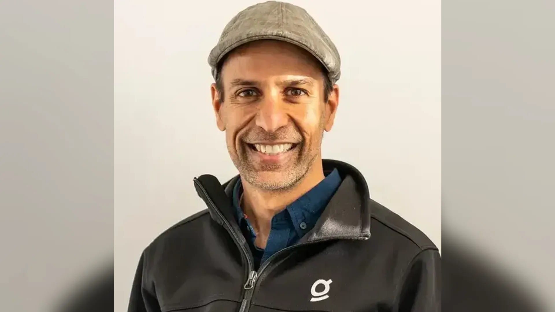 Arvind Jain, founder and CEO of Glean, in a flat cap and Glean-branded jacket