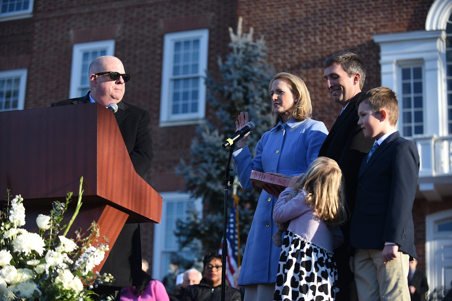 Brooke Lierman takes the oath of office as comptroller of Maryland, right hand raised, speaking at an outdoor podium.