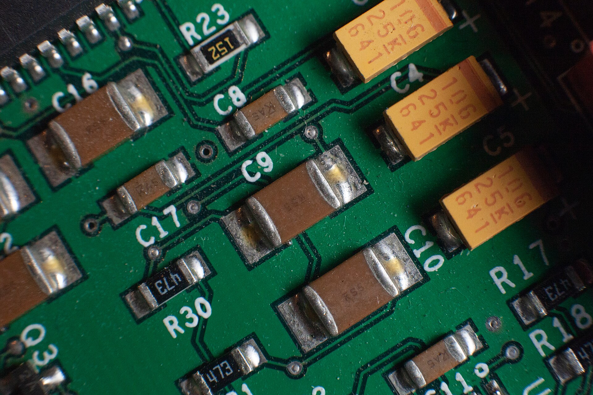 Close-up of multilayer ceramic capacitors soldered onto a green circuit board