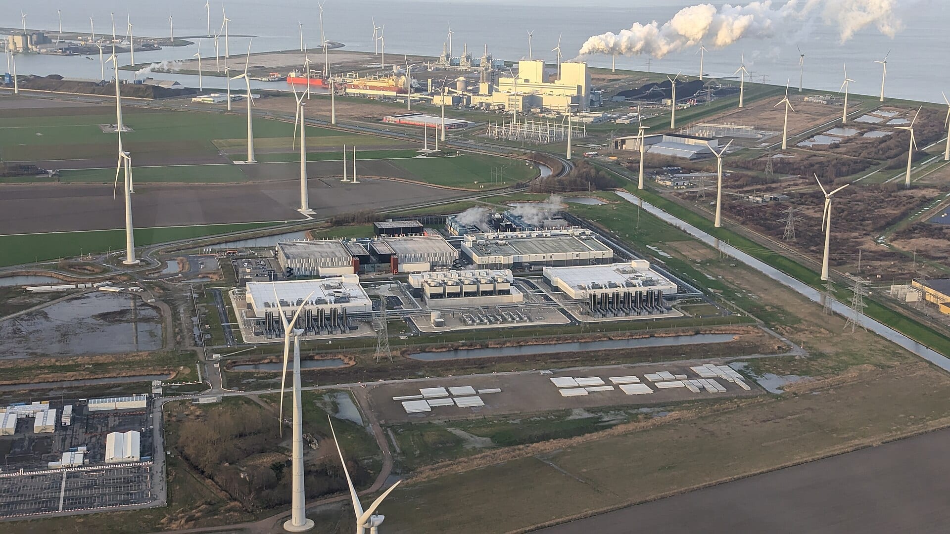 Aerial view of Google's data center campus at Eemshaven, Netherlands, surrounded by wind turbines and transmission lines