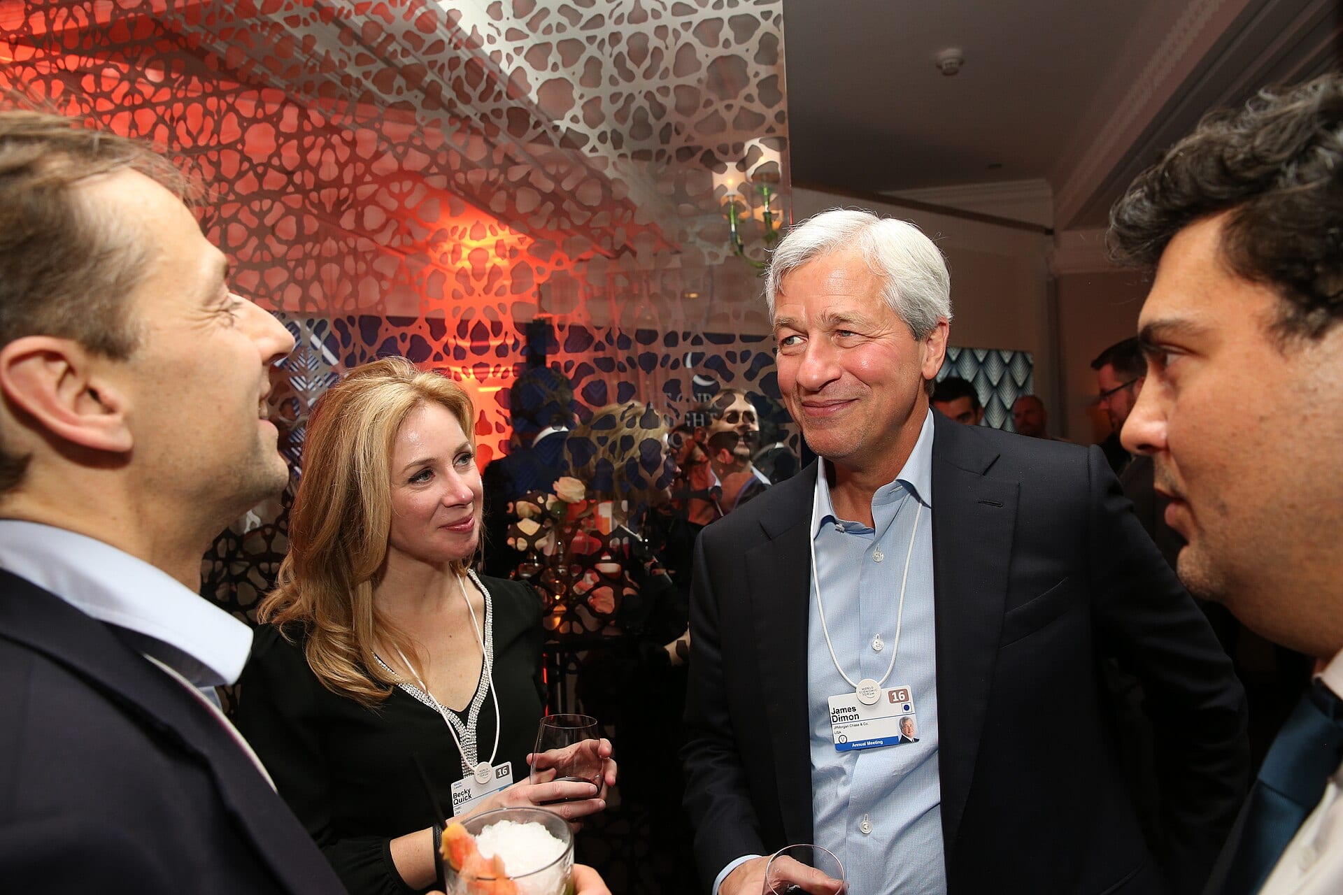 Jamie Dimon, wearing his World Economic Forum badge, talks with attendees at a Davos reception