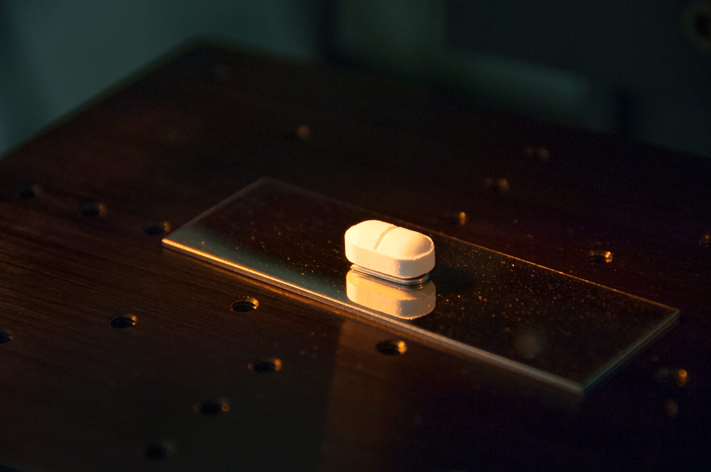 A white pill under a laboratory light during pharmaceutical research