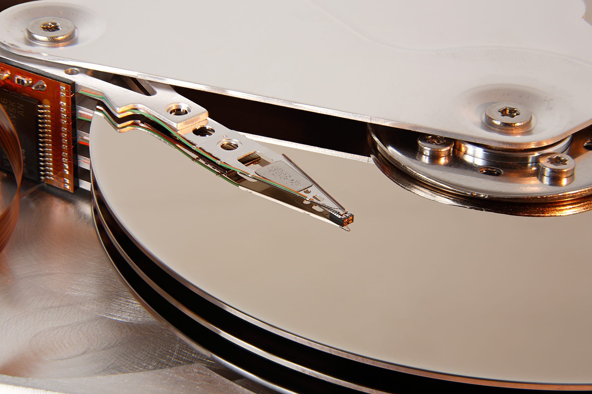 A hard drive's read-write head on its actuator arm, hovering over the platters of a hard disk drive