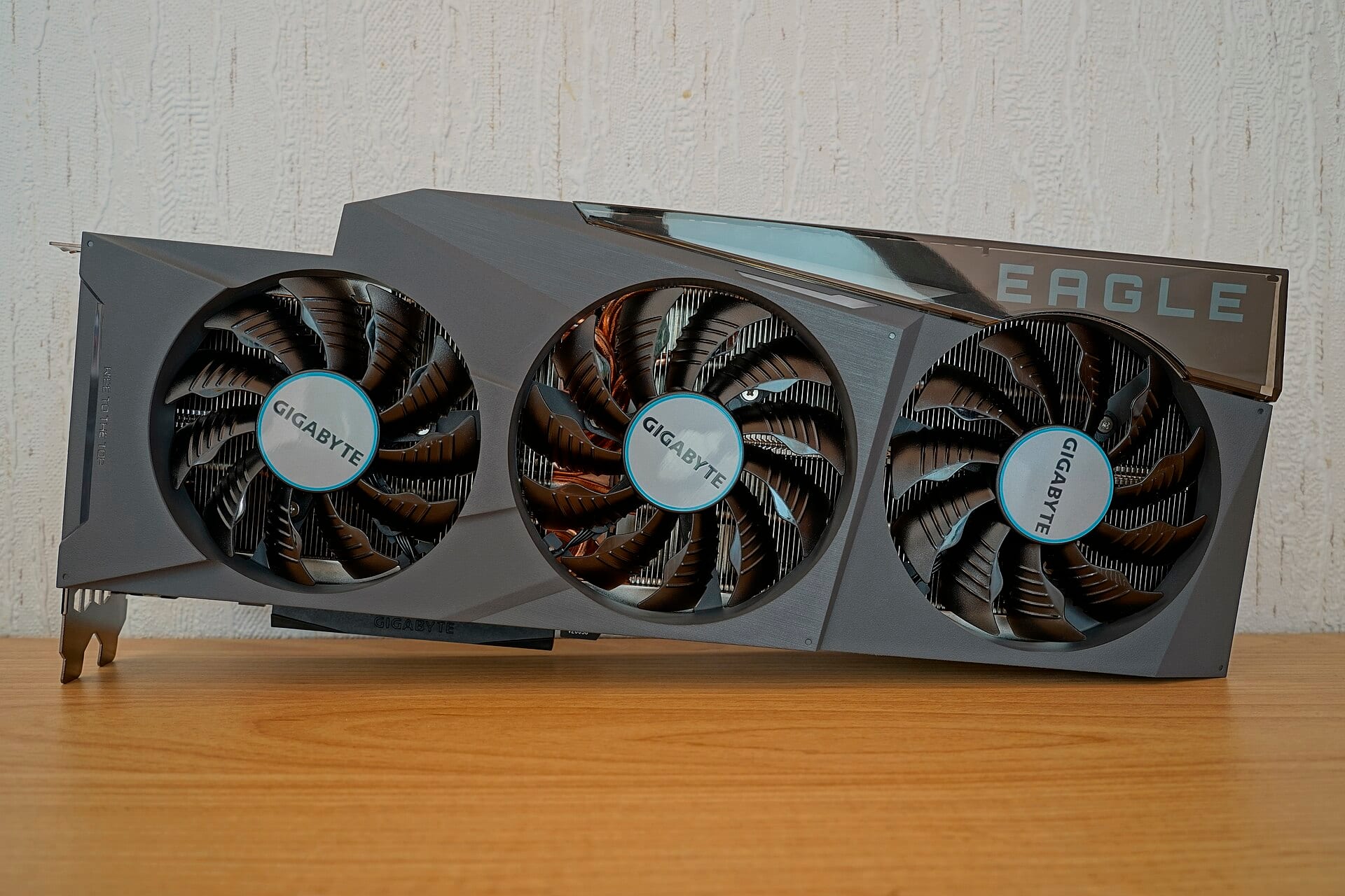 A Gigabyte GeForce RTX 3090 graphics card with three cooling fans on a wooden surface.