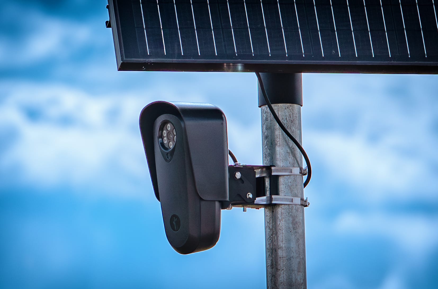 A Flock Safety automated license plate reader camera on a pole against a blue sky
