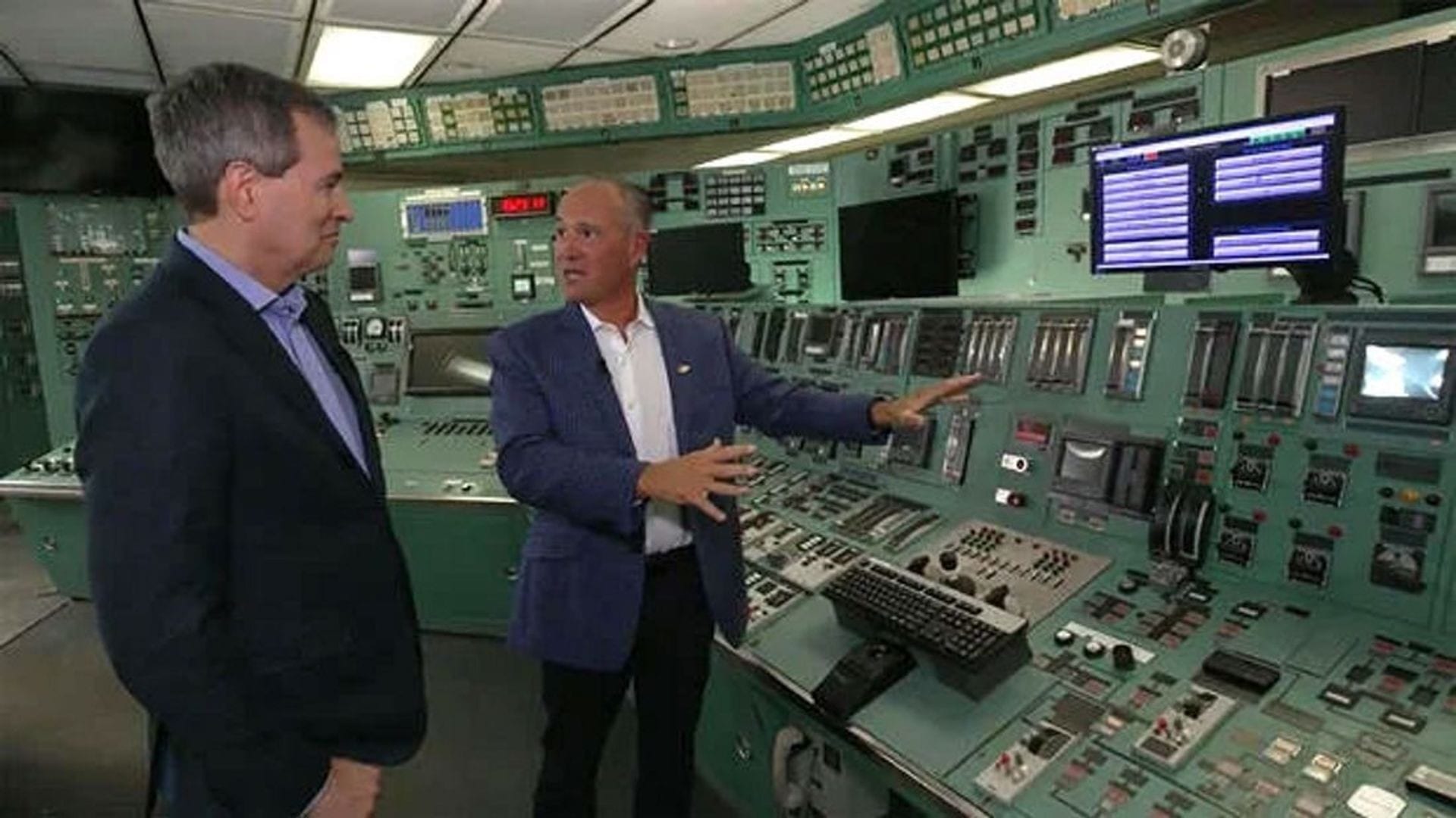 Constellation CEO Joe Dominguez gestures toward the control panels in the Crane Clean Energy Center control room while speaking with another executive