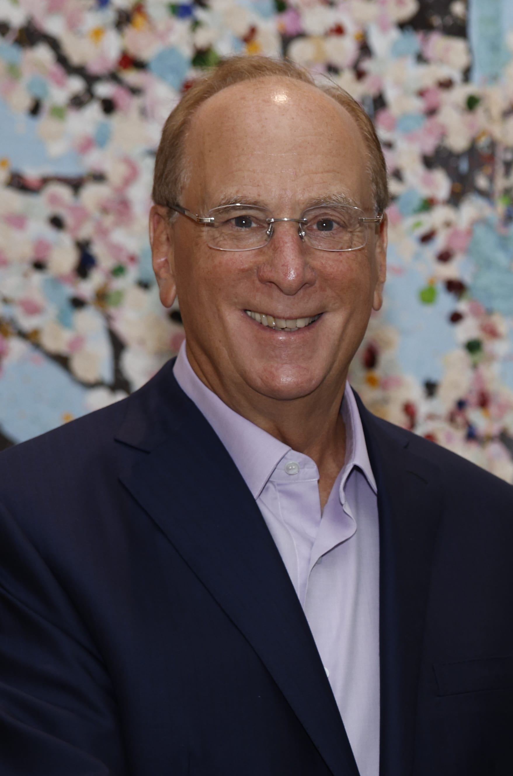Larry Fink, BlackRock's chairman and chief executive, smiling in a dark suit against a colorful backdrop
