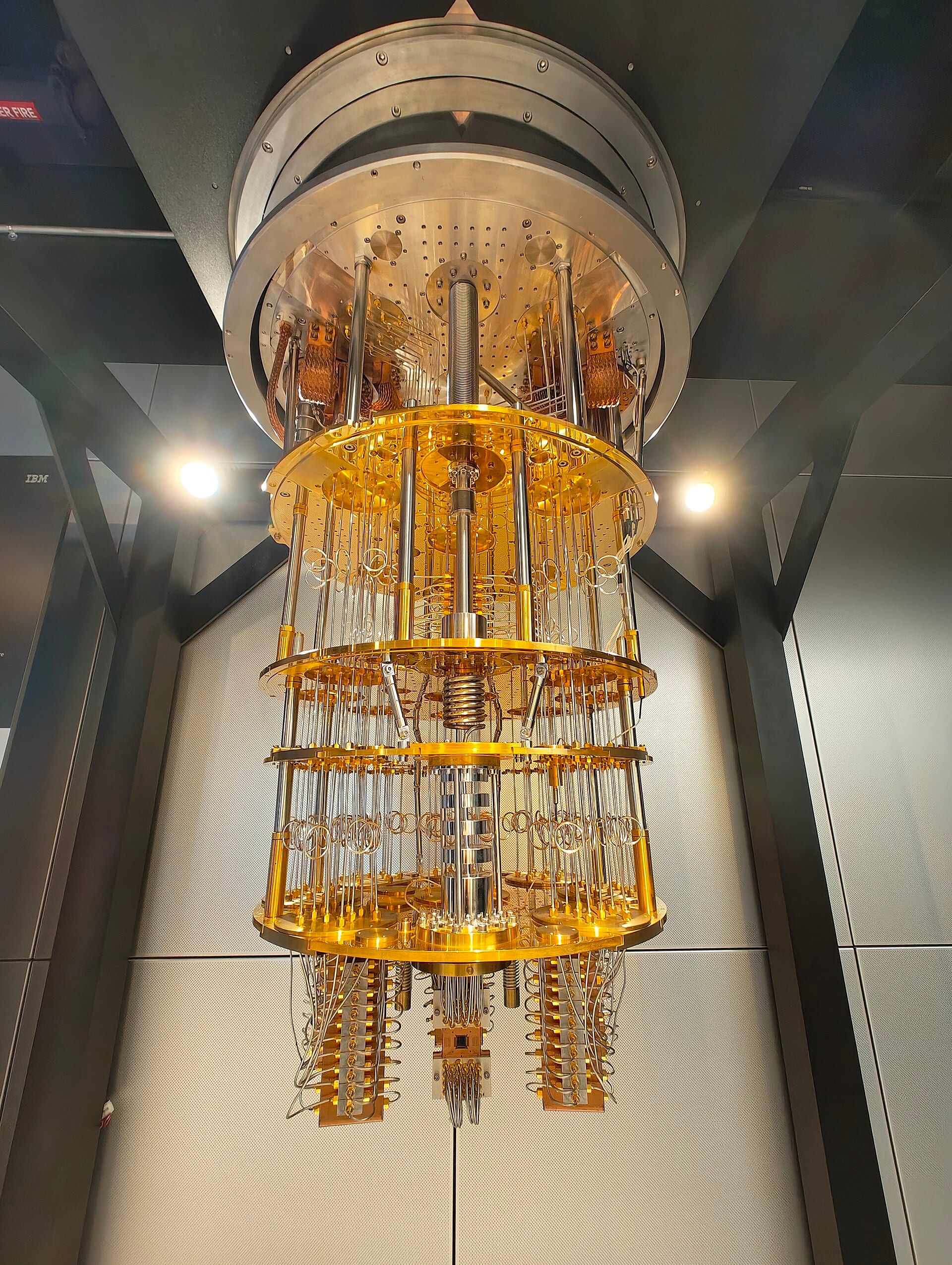The golden chandelier of an IBM Quantum System One superconducting quantum computer, its cryostat opened to show stacked plates and wiring.