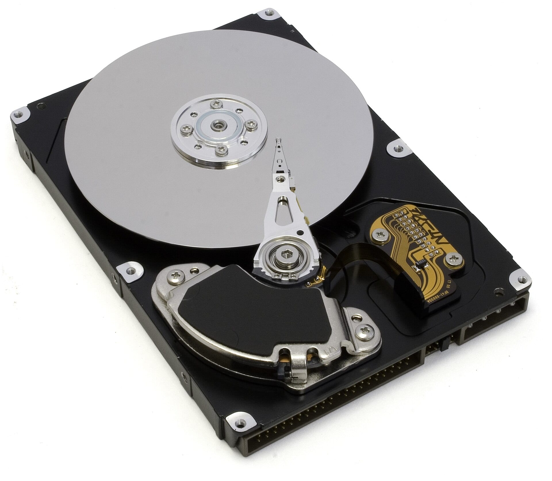 An opened hard disk drive showing its reflective spinning platter and read-write actuator arm.