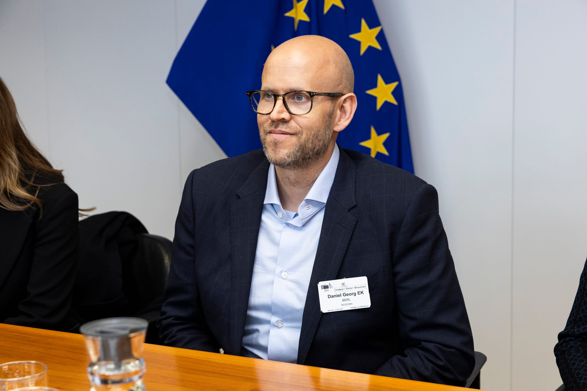 Daniel Ek, co-founder of Spotify, seated at a meeting table with a European Union flag behind him