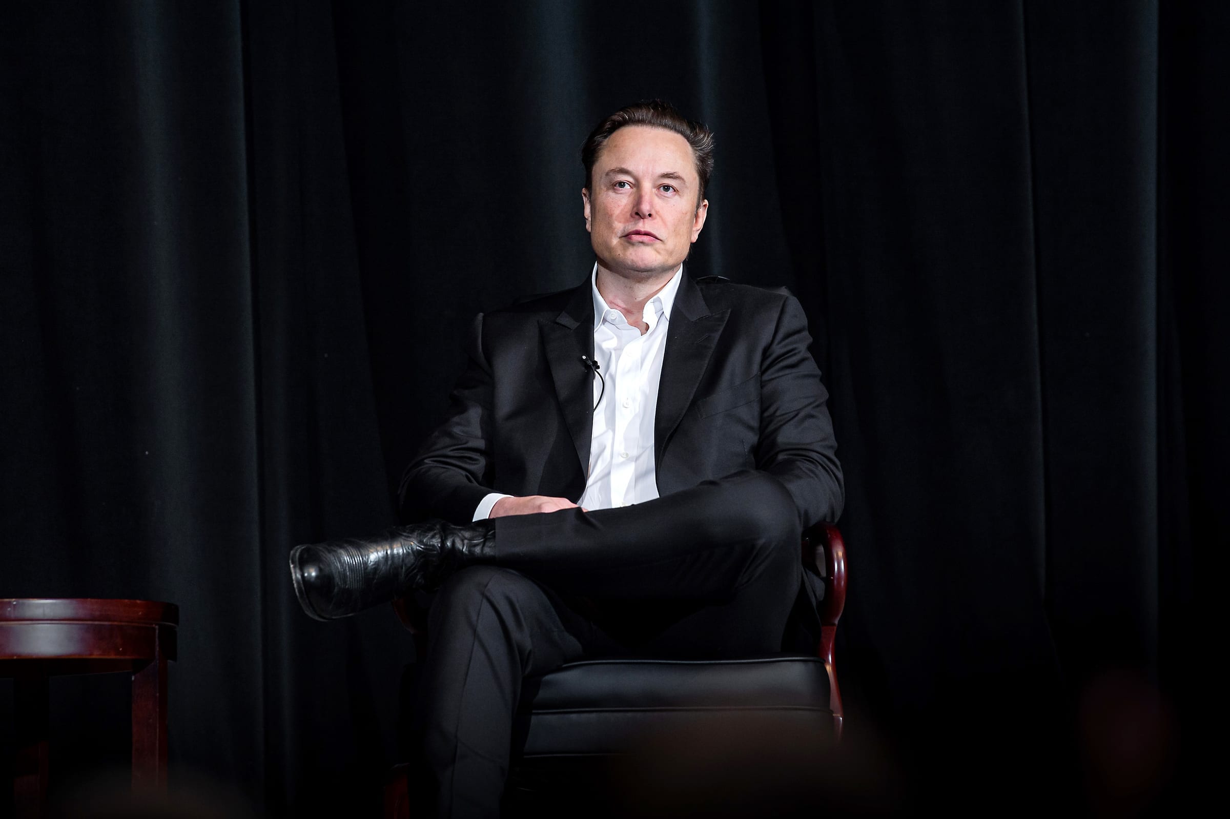 Elon Musk seated on a stage, facing the camera