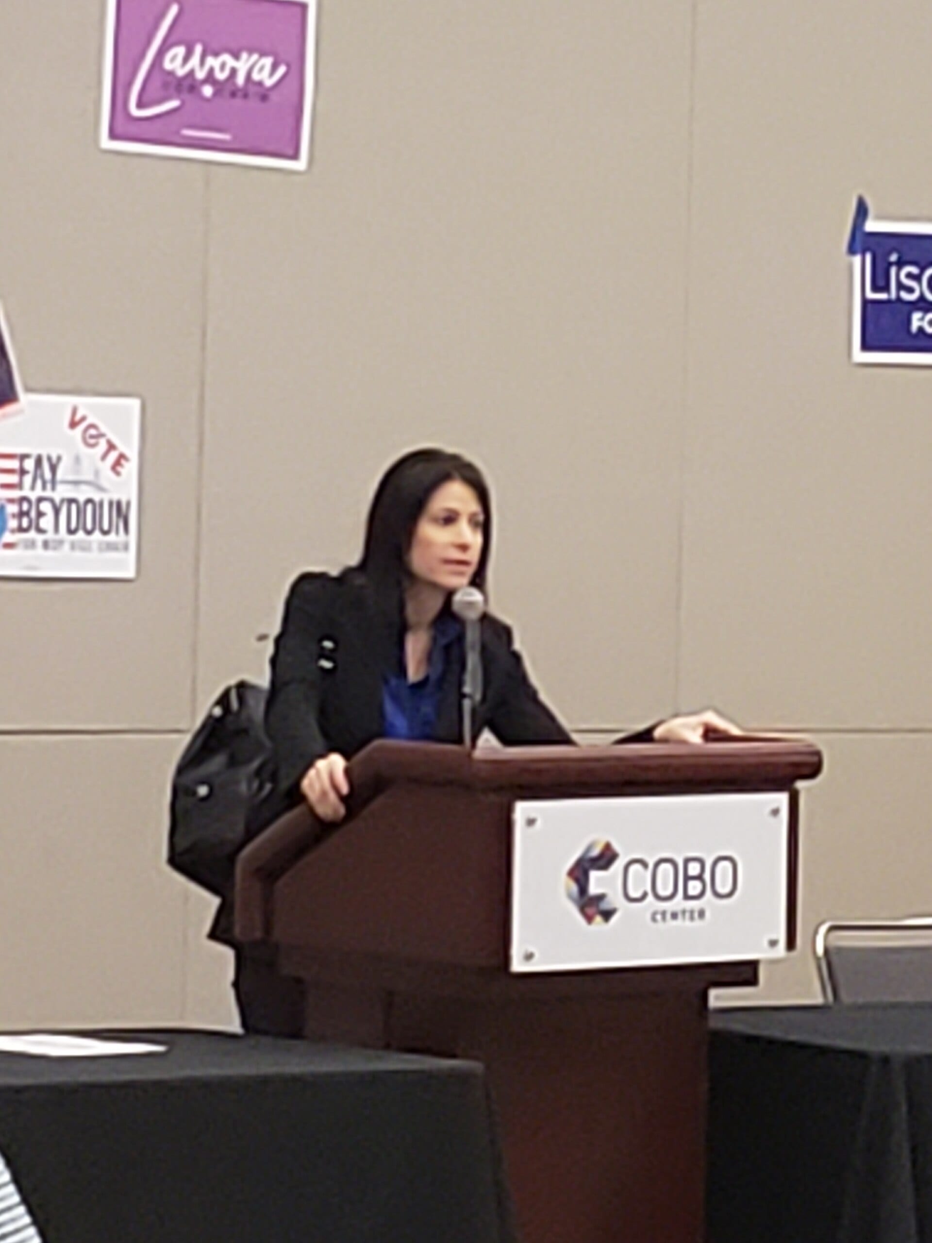 Michigan Attorney General Dana Nessel speaking at a podium at a Michigan Democratic Party convention.