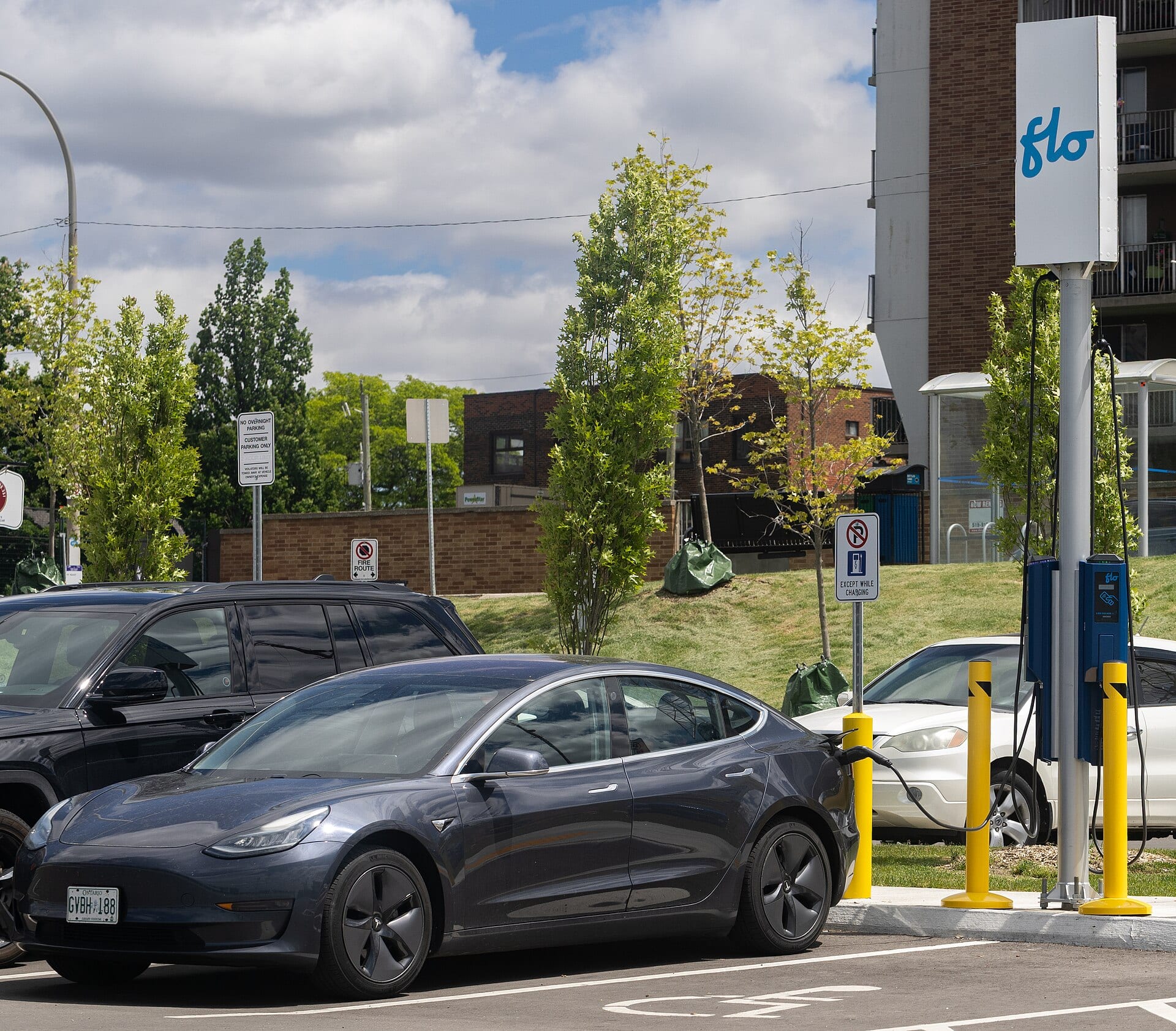 A dark grey Tesla Model 3 charging at a public station in Windsor, Ontario