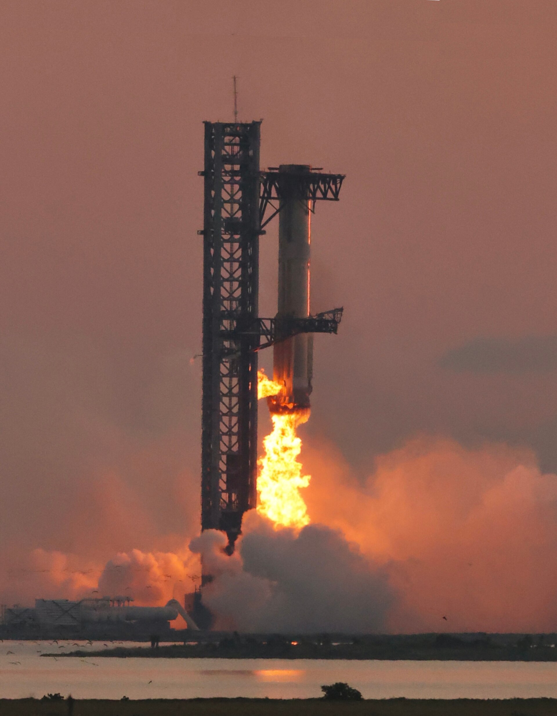 A Super Heavy booster is caught between the launch tower's arms at Starbase during Starship's fifth flight test