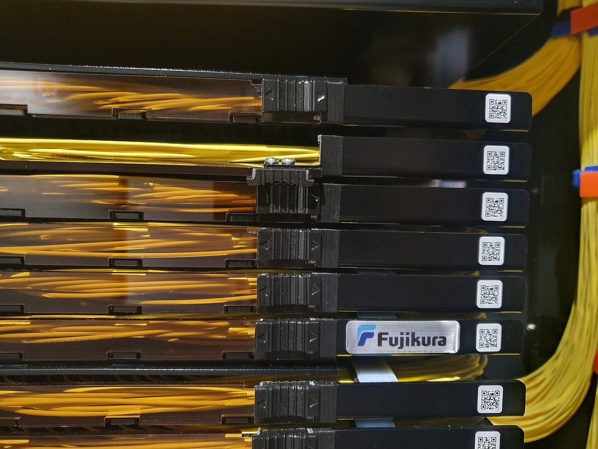 Fujikura-branded fiber patch panels with coiled yellow optical pigtails in a rack