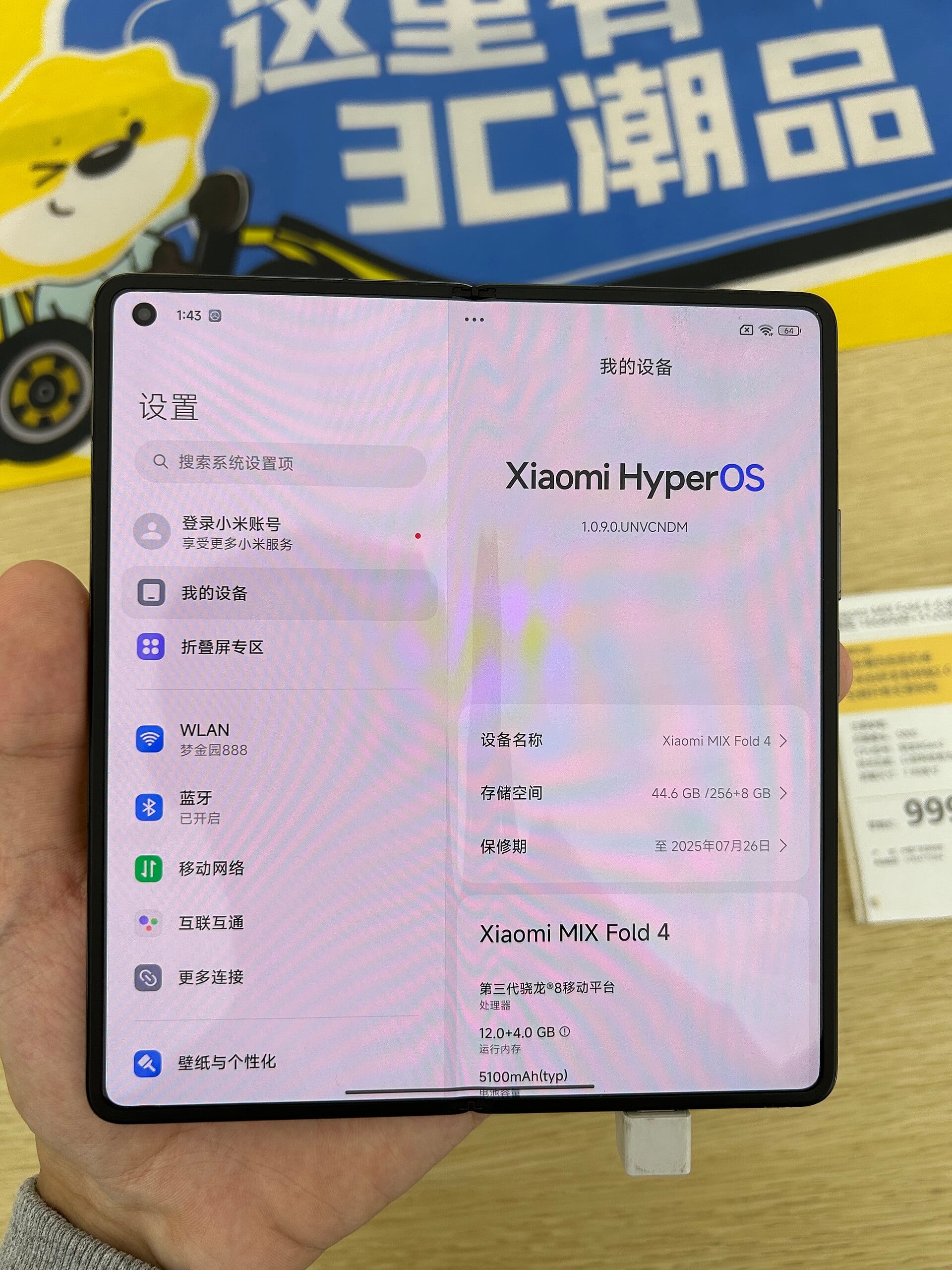 Xiaomi MIX Fold 4 unfolded in a retail store, its screen showing Xiaomi HyperOS and the device name