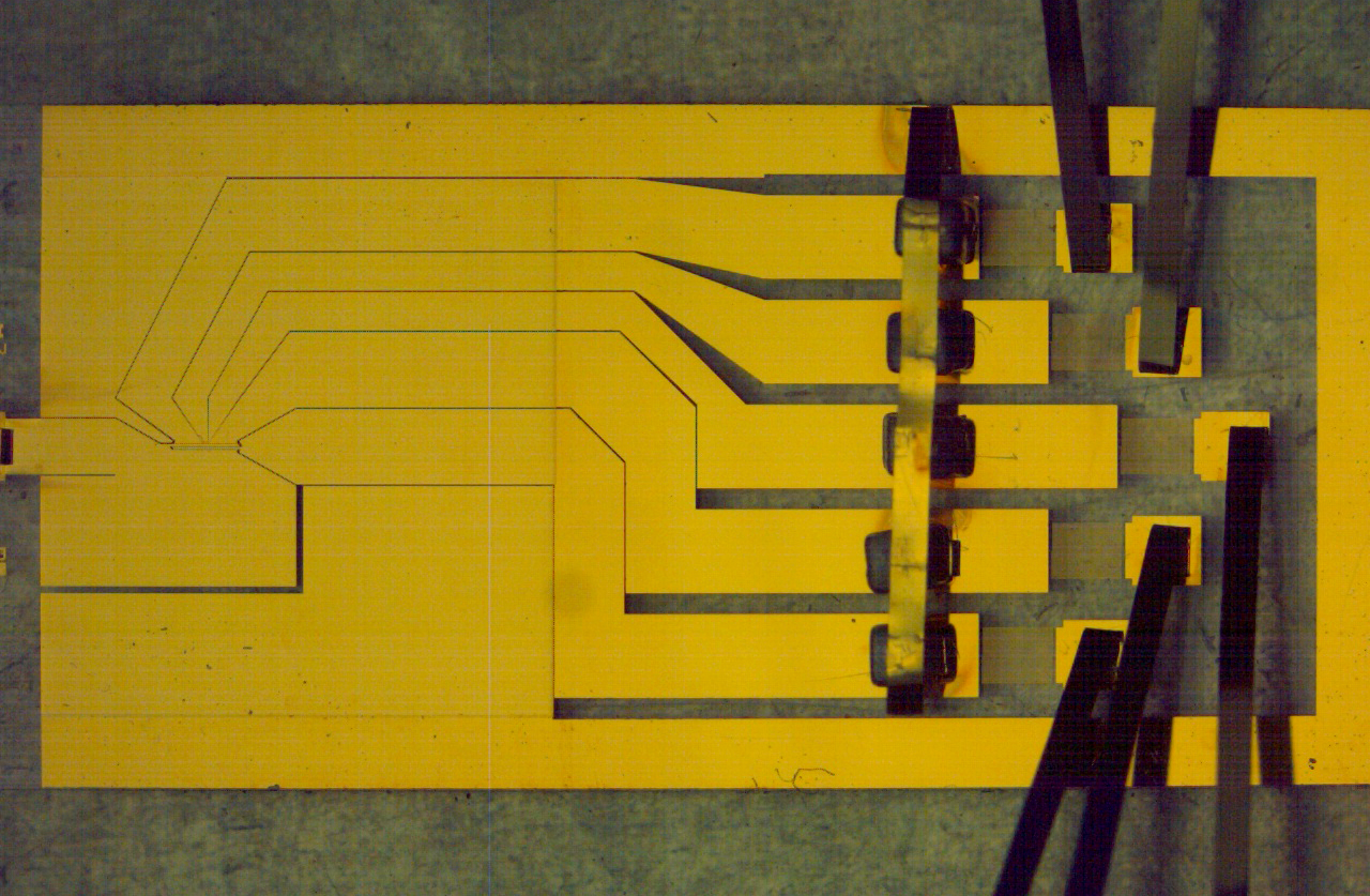 A gold planar ion trap chip with electrodes and wire bonds, photographed at NIST
