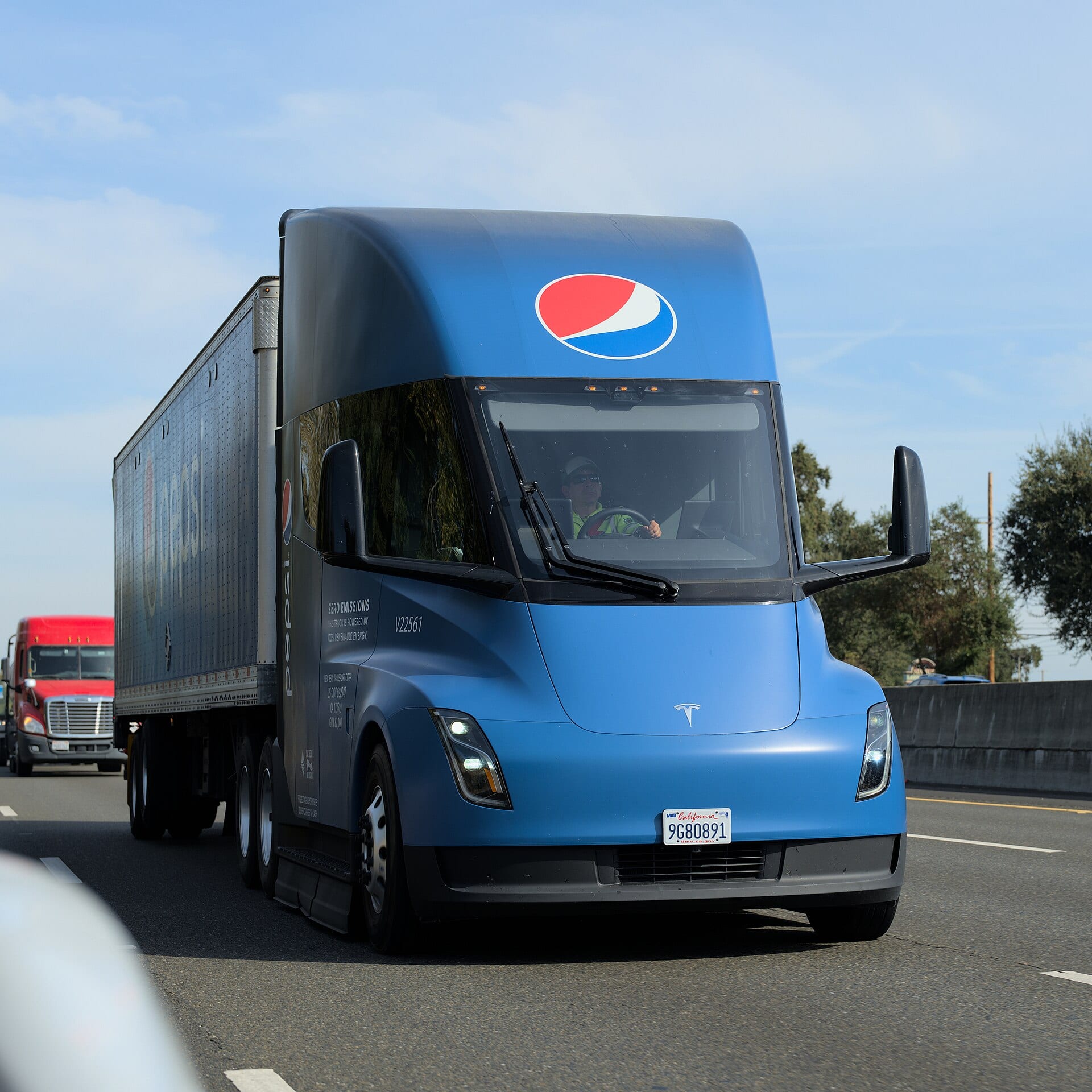 A blue Tesla Semi with PepsiCo branding hauling a trailer on a California freeway