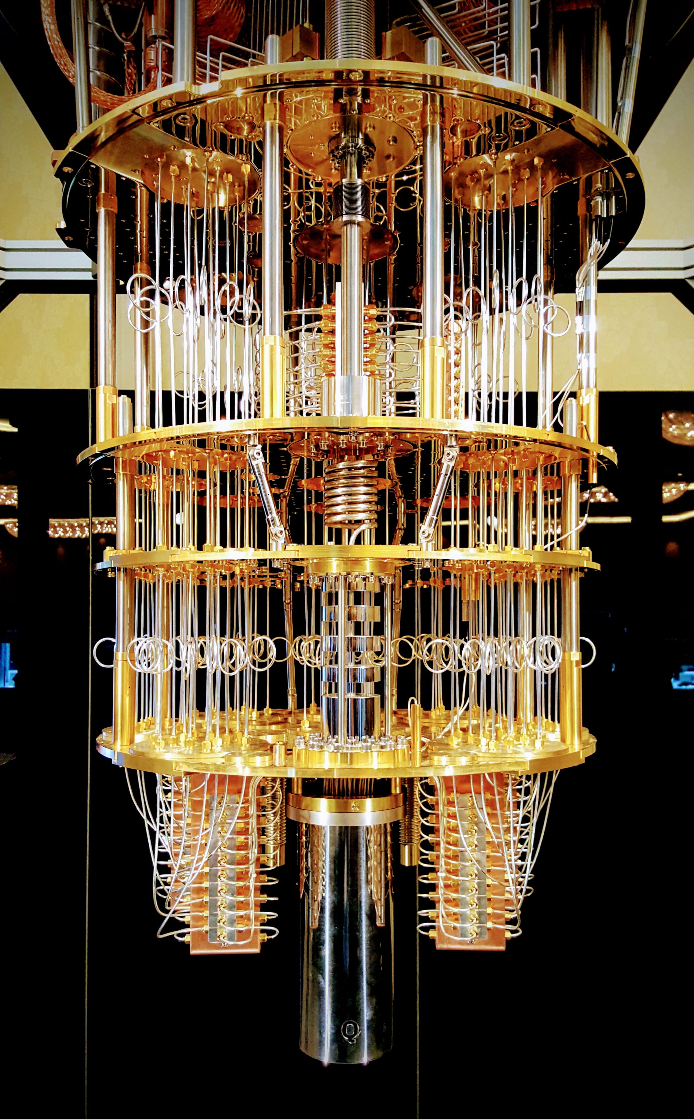 The gold chandelier-like interior of an IBM Q quantum computer, with tiers of cryostat plates, coaxial wiring and cooling stages descending to the processor at the bottom.