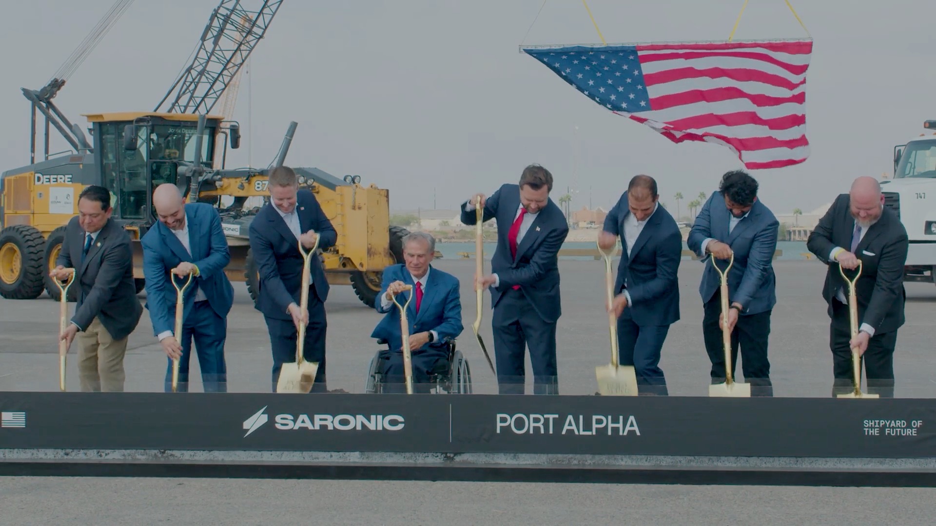Officials and Saronic executives break ground on the Port Alpha shipyard at Brownsville, Texas, with gold shovels under a large American flag