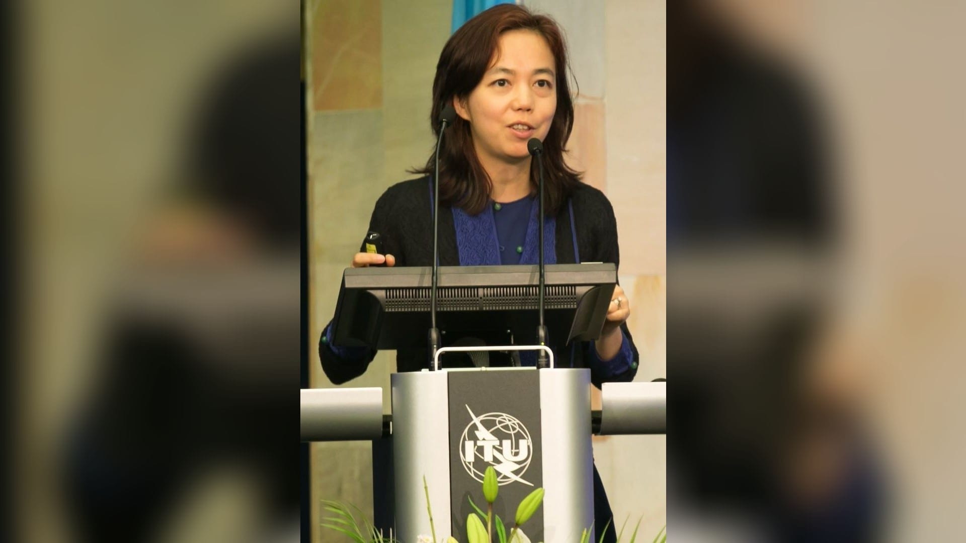 Fei-Fei Li speaking at a podium at the ITU AI for Good summit in Geneva in 2017