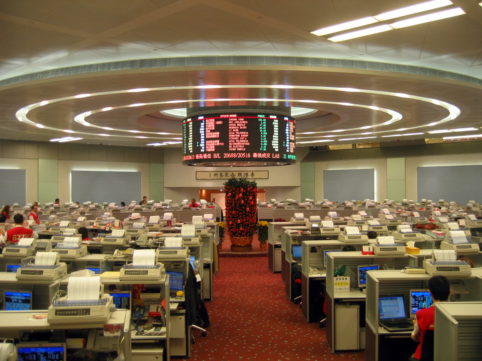 The Hong Kong Stock Exchange trading hall with rows of terminals and the Hang Seng quotation board overhead