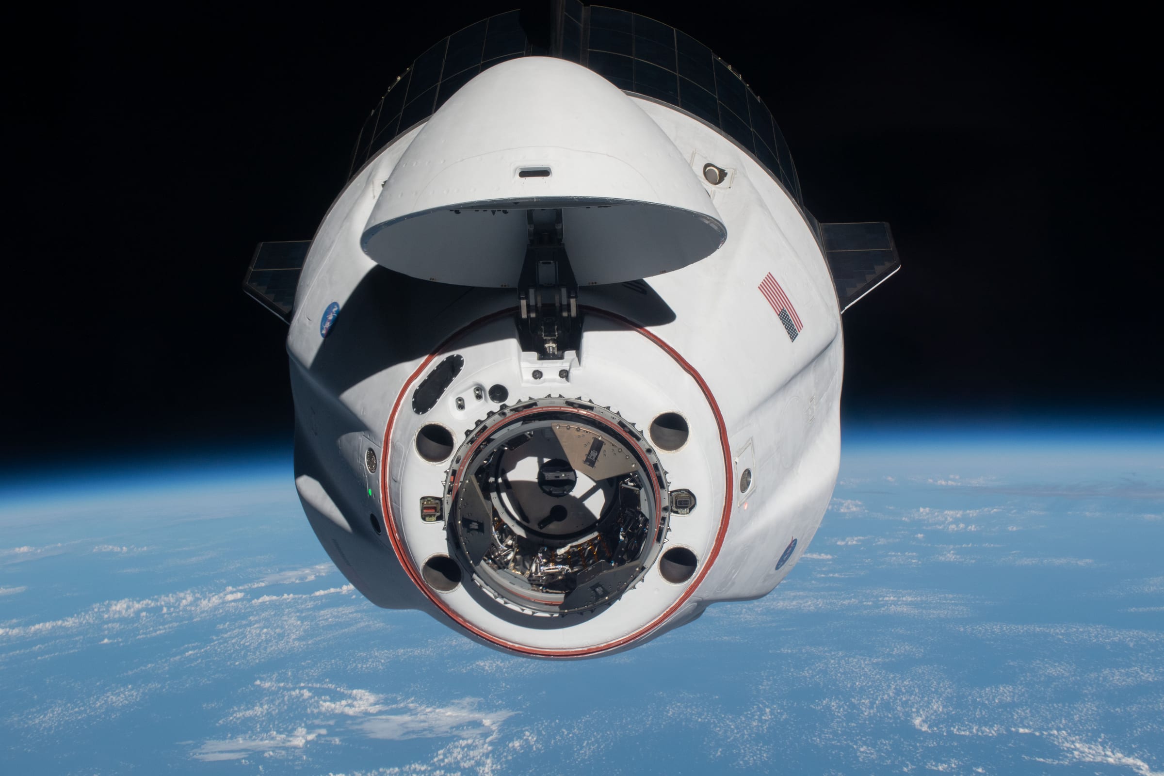 SpaceX's Crew Dragon Endeavour capsule approaching the International Space Station, docking port open, with Earth below