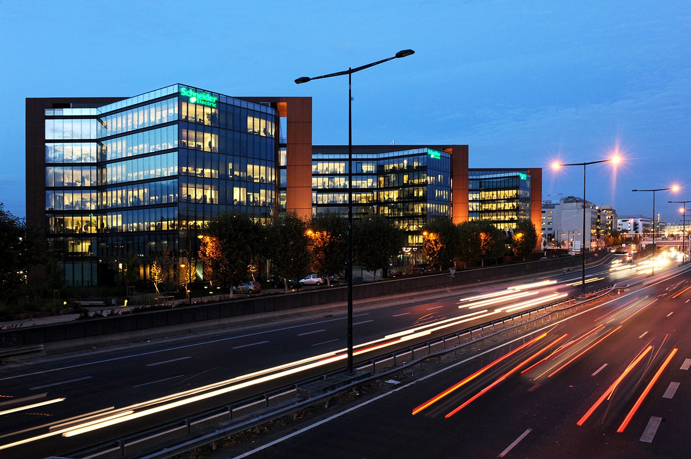 Schneider Electric's group headquarters, The Hive, lit at dusk beside a motorway outside Paris