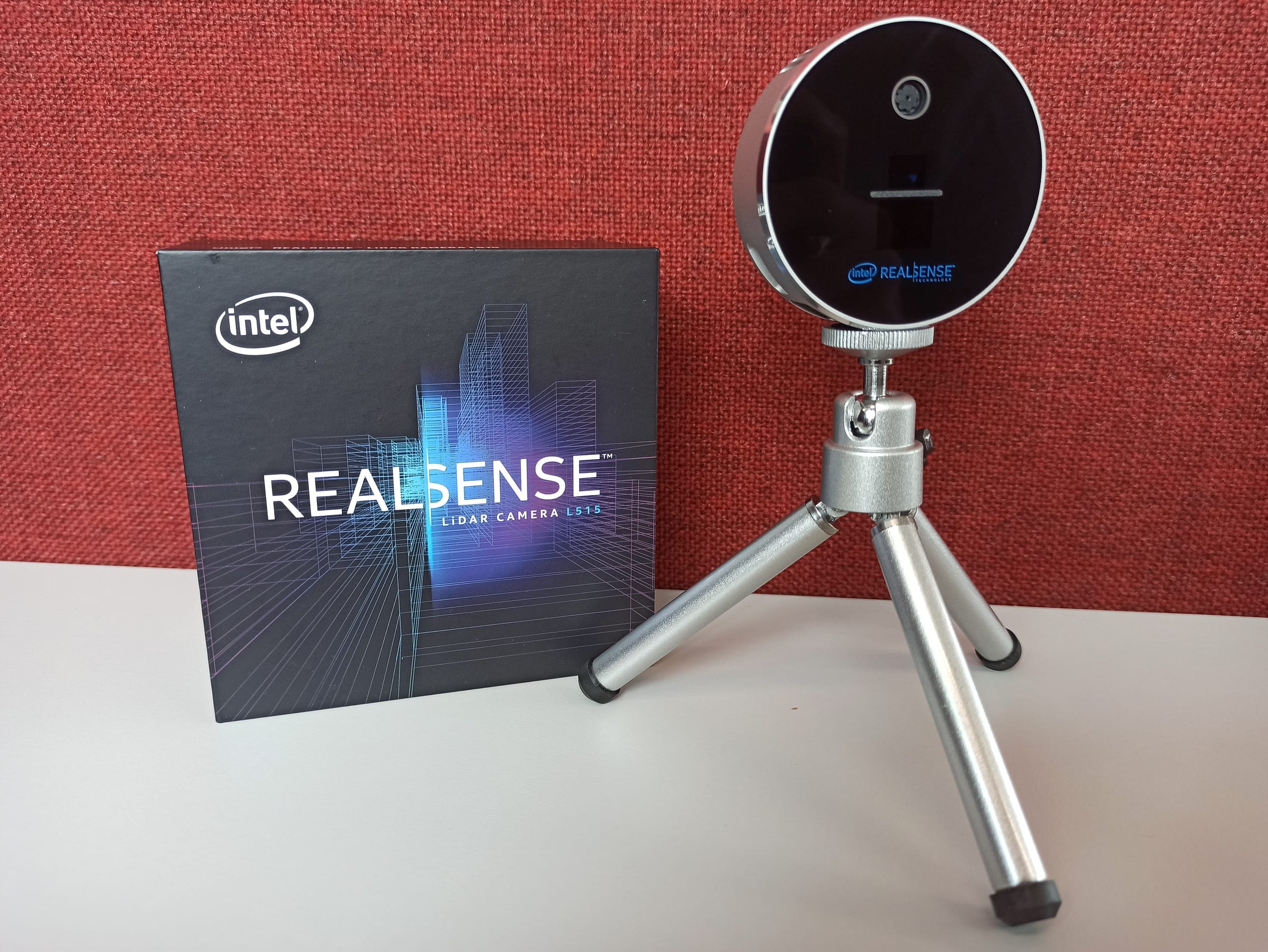 Intel RealSense L515 lidar depth camera on a small tripod next to its retail box