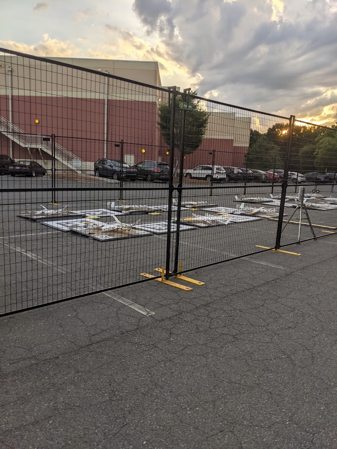 Rows of small drone delivery launch pads behind a temporary fence at dusk