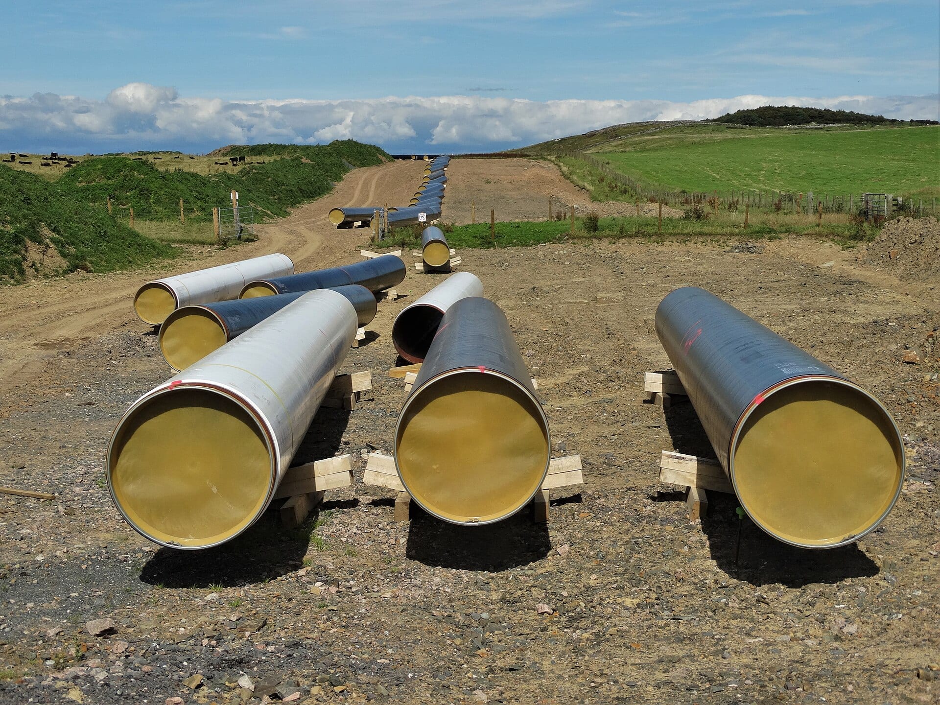 Large coated natural gas pipe joints stacked along a cleared right of way under construction