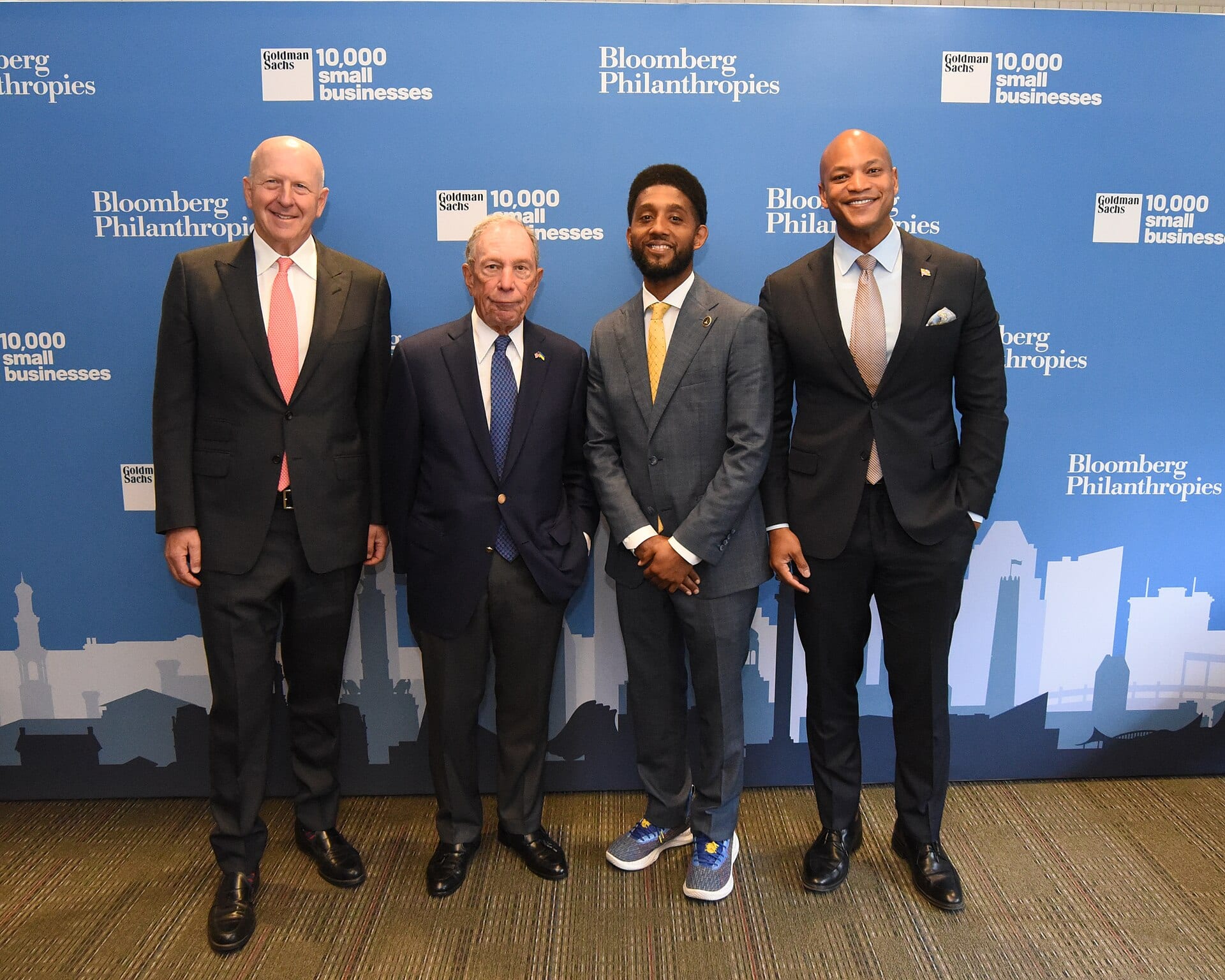 Goldman Sachs chief executive David Solomon, left, standing with Michael Bloomberg, a 10,000 Small Businesses graduate and Maryland governor Wes Moore in front of Goldman Sachs and Bloomberg Philanthropies banners