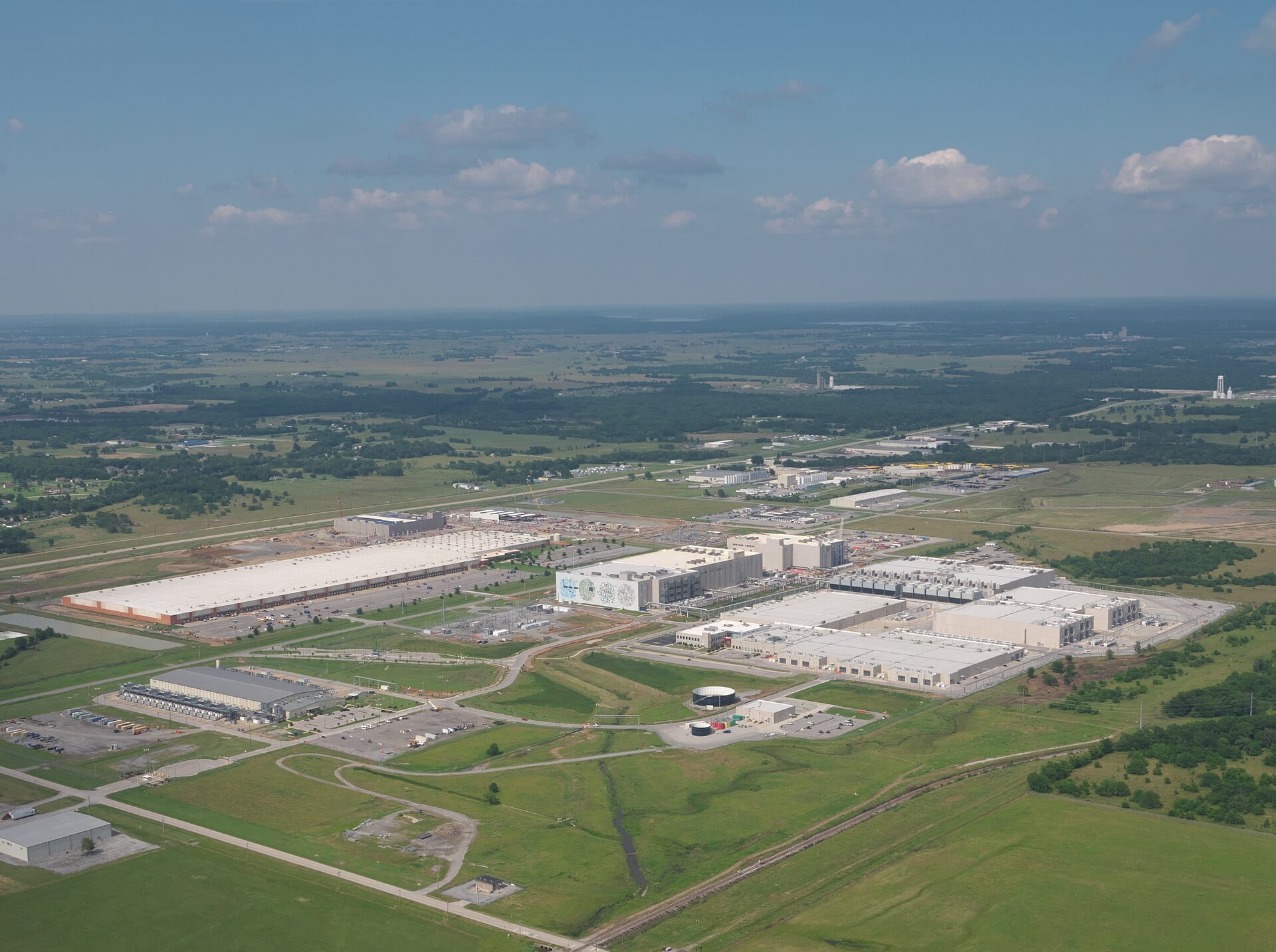 Aerial view of a Google data center campus spreading across green fields