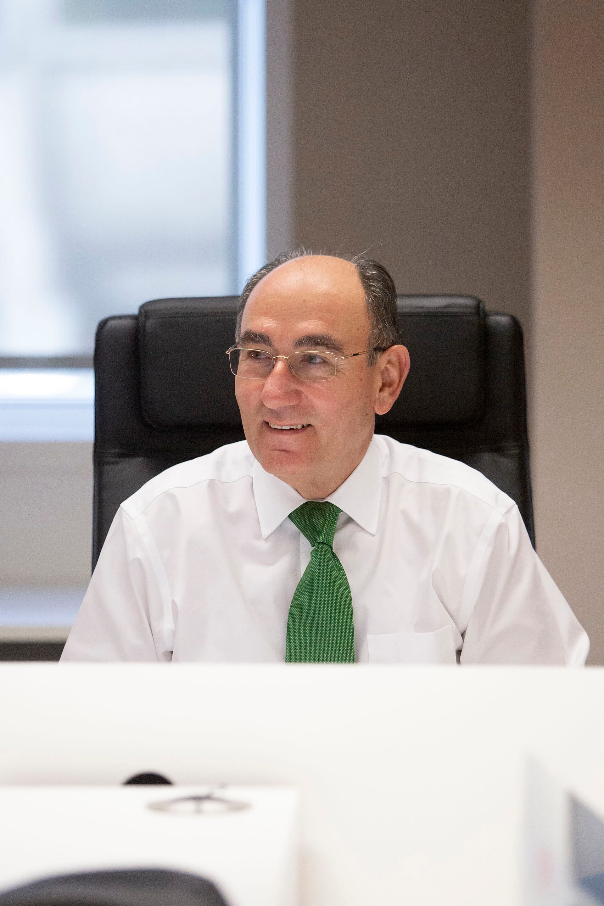Ignacio Sánchez Galán, chairman of Iberdrola, seated at a desk in a white shirt and green tie