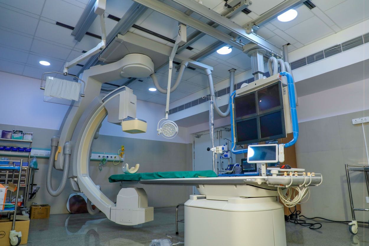 A Philips interventional fluoroscopy system, a C-arm over a patient table with ceiling-mounted monitors, installed in a hospital cath lab.