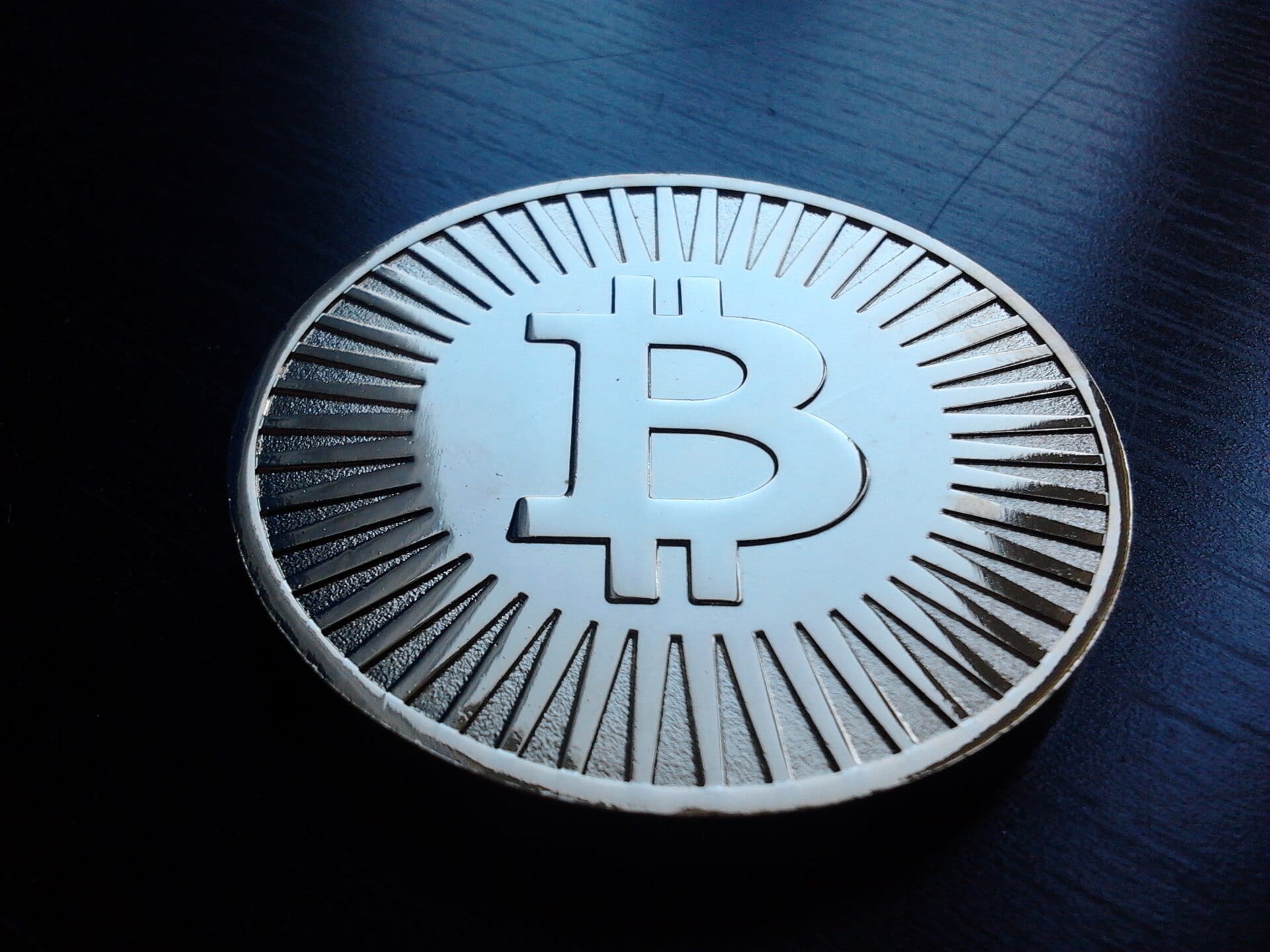 A physical bitcoin token photographed on a dark surface