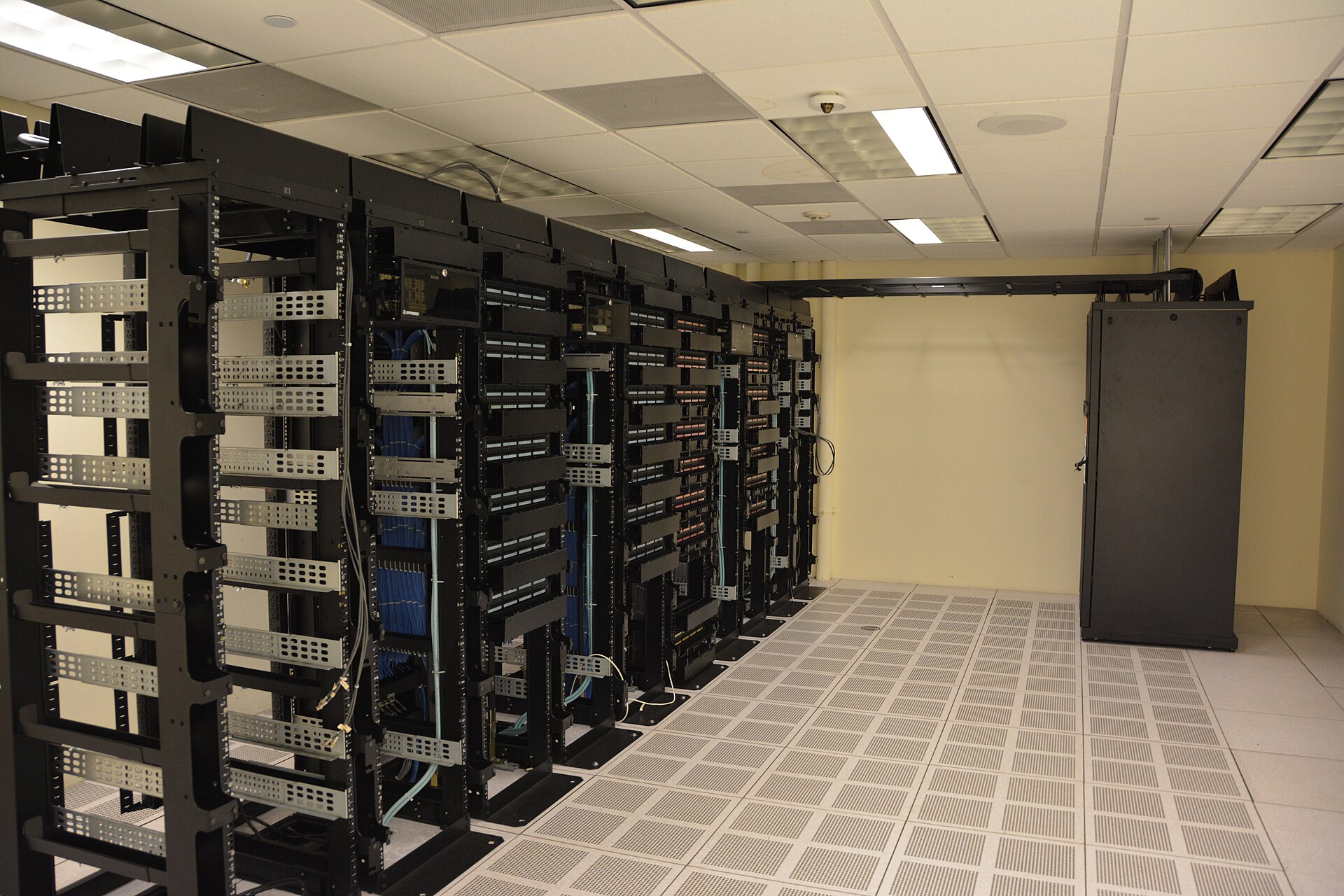 Rows of server racks in a commercial data centre, cabling running overhead